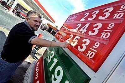 A service station employee changes the price tag for gasoline at their station in Los Angeles, California, in November 2008